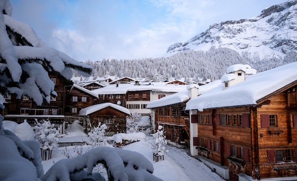 Chalet buildings covered in deep snow with mountains behind